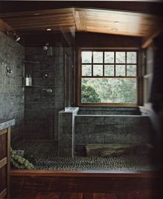 a bathroom with a large window and tiled shower stall in the middle of the room