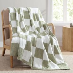 a green and white checkered blanket sitting on top of a chair next to a window