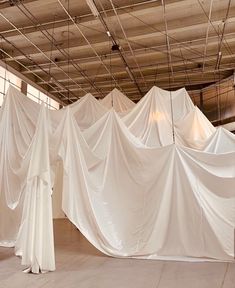 several white drapes are hanging from the ceiling in an empty room with no people