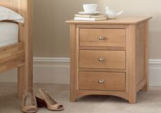 a pair of shoes sitting on the floor next to a nightstand with a cup and saucer