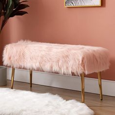 a pink bench sitting in front of a plant on top of a hard wood floor