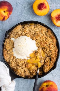 a skillet with ice cream and peaches on it next to some sliced peaches