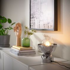 a table with a lamp and some books on it next to a potted plant