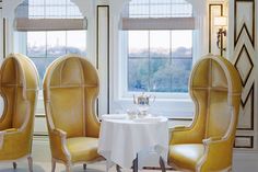 two yellow chairs sitting next to each other in front of a table with a cup on it