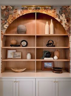 a wooden shelf with vases and other items on it's shelves in a room