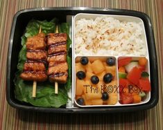 a bento box filled with meat, rice and fruit