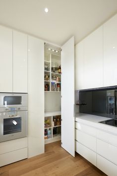 a kitchen with white cupboards and an oven in the center, next to a wooden floor