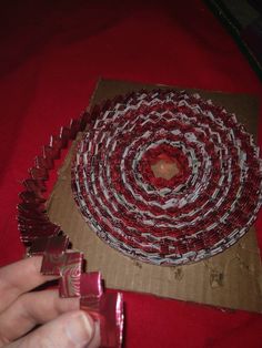 someone is making a red and white paper flower on top of a brown cardboard box