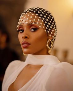 a woman wearing a head wrap and pearls on top of her head is looking off to the side