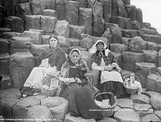 three women sitting on top of large rocks next to each other with baskets in their hands