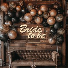 the bride to be sign is surrounded by black, gold and silver balloons in front of a couch