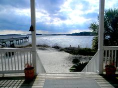 an open porch with a view of the beach and pier in the distance on a cloudy day