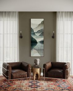 a living room with two leather chairs and a painting on the wall behind them,