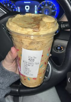 a person holding up a cup of ice cream in their hand with a price label on it