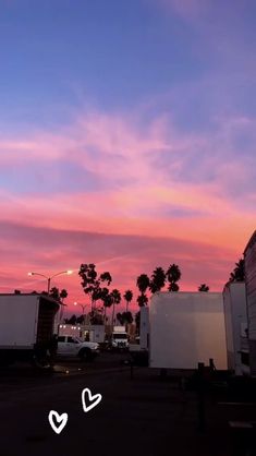 the sky is pink and blue with white hearts in front of palm trees at sunset