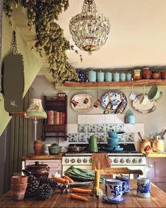 an old fashioned kitchen with lots of pots and pans on the shelf above the stove