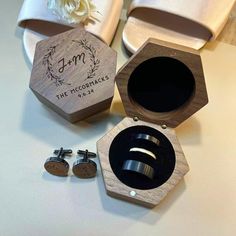 two wooden boxes with wedding rings in them on a table next to some white flowers