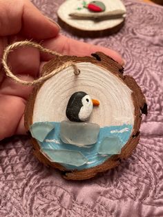 a hand holding a piece of wood with a penguin on it