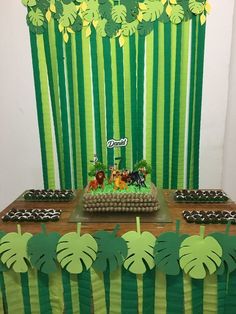 a table topped with cake covered in green frosting and jungle animals on top of it