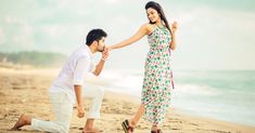 a man kneeling down next to a woman on the beach