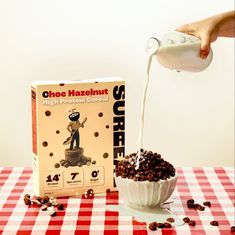 a person pours milk into a bowl filled with chocolate chips next to a box of cereal