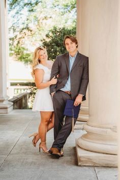 a man and woman standing next to each other in front of an old white building