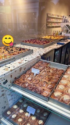 a display case filled with lots of different types of donuts and pastries in front of a smiling face