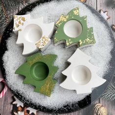 three white and green dishes sitting on top of a plate covered in snow next to christmas decorations