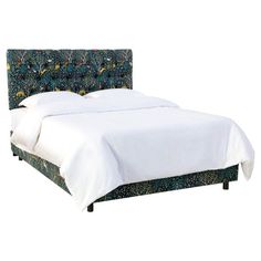 an upholstered bed with white linens and blue floral headboard, against a white backdrop