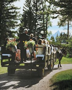 people are riding in the back of a horse drawn carriage with flowers on it's back