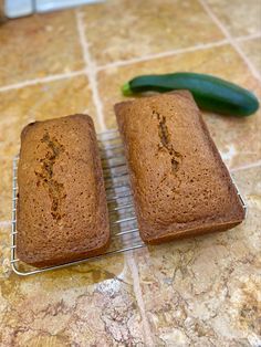 two pieces of bread sitting on top of a cooling rack next to a cucumber