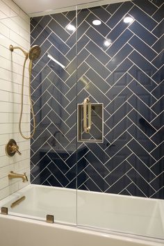 a bathtub and shower in a bathroom with blue tiles on the wall, gold fixtures