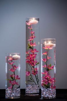 three vases with flowers and candles in them