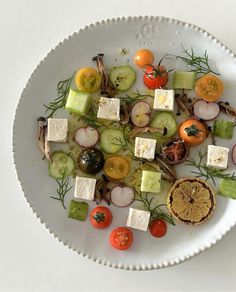 a white plate topped with cucumbers, tomatoes and cheese