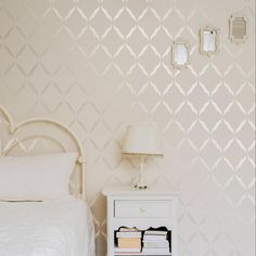 a white bed sitting next to a night stand with a lamp on top of it