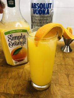 a glass filled with orange juice next to an empty bottle