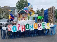 a sign that says sophmores on it in front of a house with balloons and streamers