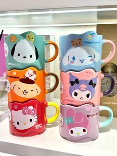 four hello kitty coffee mugs sitting on top of a counter next to each other