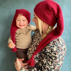 a woman holding a baby wearing a red hat