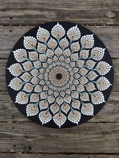 a black plate with white and blue designs on it sitting on top of a wooden table