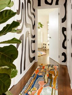 the hallway is decorated with black and white wallpaper, an orange rug, and a large green plant