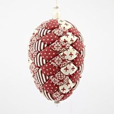 a red and white ornament hanging from a hook on a string with snowflakes all over it