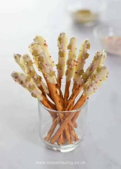 a glass filled with lots of pretzels sitting on top of a white table