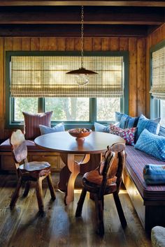 a table and chairs in a room with wood paneled walls, windows, and wooden flooring