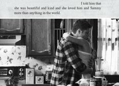 a man and woman hug in the kitchen while they are preparing food for their dinner