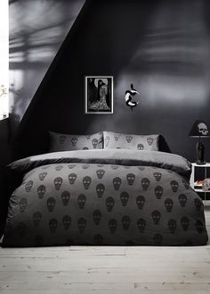 a black and white photo of a bedroom with skulls on the comforter, bedding