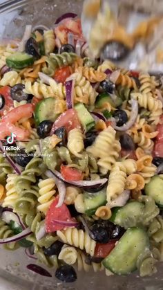 pasta salad with cucumber, olives, tomatoes and onions in a glass bowl