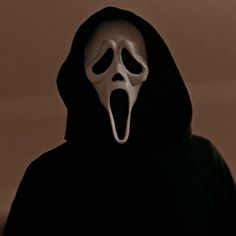 a person in a black hoodie with a white mask on and mouth wide open