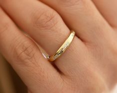 a woman's hand with a gold wedding band and diamond ring on her finger