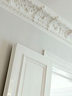 an ornate crown molding on the ceiling above a window in a room with white walls